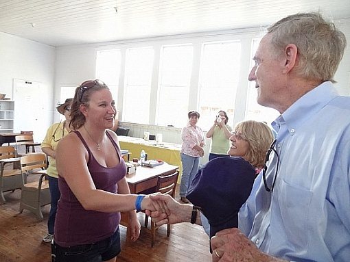 A woman shaking hands with an older man.