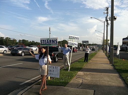 A group of people holding signs on the side of the road.